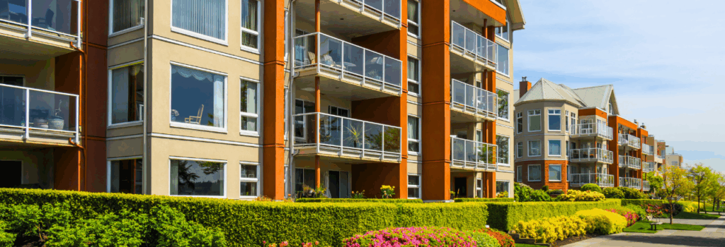 exterior view of apartment building withy shrubs and flowers lining the outside near the street