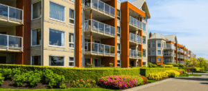 exterior view of apartment building withy shrubs and flowers lining the outside near the street