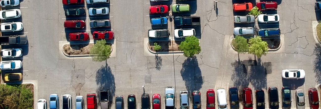aerial view of 8 rows of vehicles in a large parking lot with no shade Online Parking Permits for Apartments