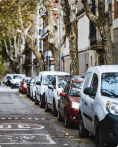 view from the street, cars parallel parked near apartment buildings